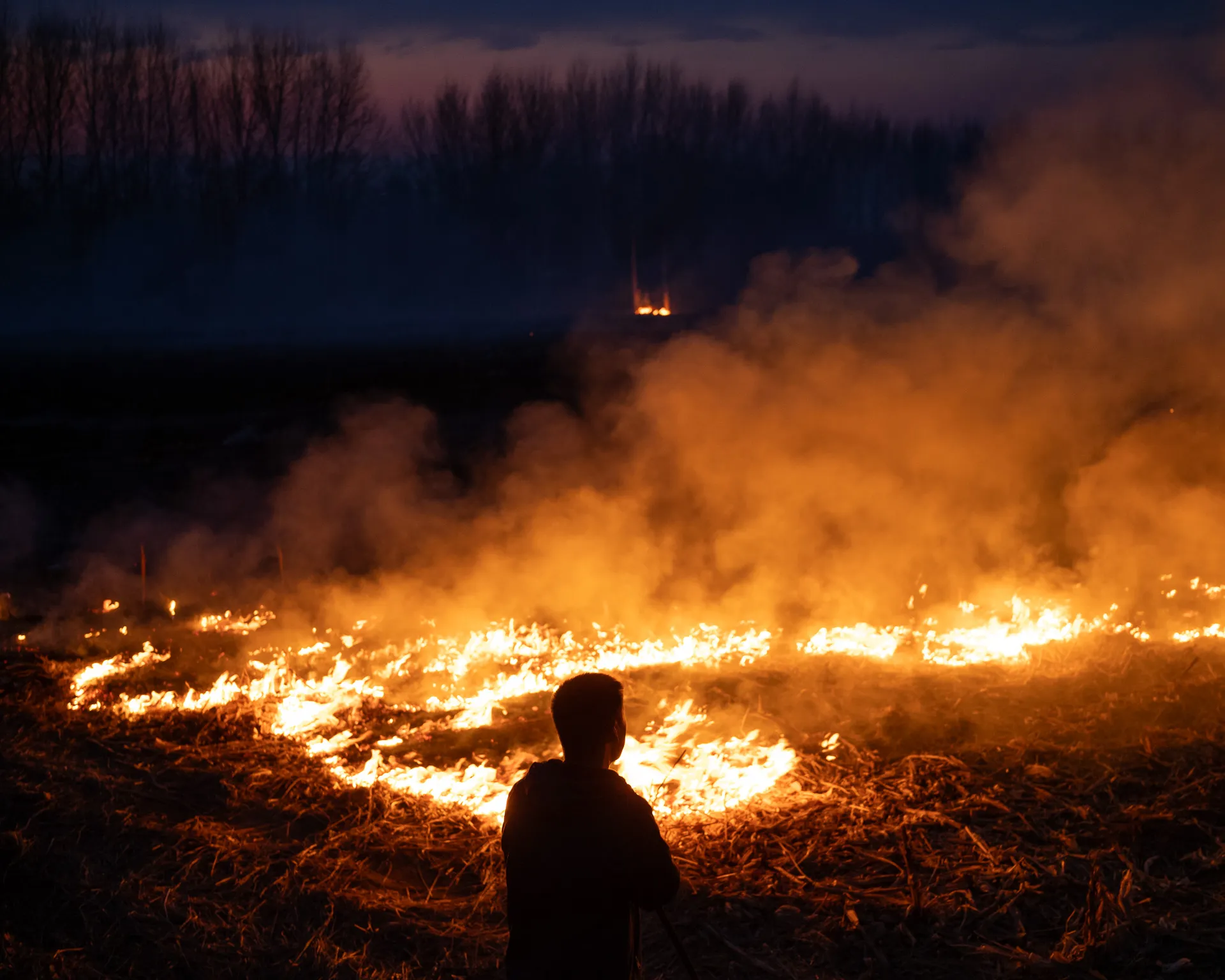 A man burning fields at dusk.